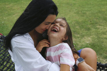 Happy mother embracing daughter on hammock - SYEF00484