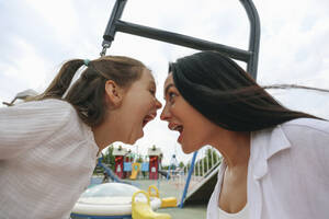 Fröhliche Mutter und Tochter haben Spaß auf dem Spielplatz - SYEF00497