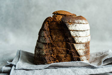 Front view of stack of rye bread slices on grey cloth napkin against blurred light background - ADSF45254