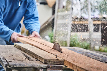 High angle of crop unrecognizable artisan in casual clothes sawing planks of wood with traditional machine in yard of farm in community of Otavalo in Ecuador - ADSF45356