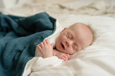 Newborn child lying on soft bed and sleeping in morning at home - ADSF45373