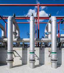 Modern exterior of construction of gray metal water pipes and tubes with circulation pumps and valves of industrial building against blue sky - ADSF45409