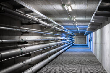 Empty underground corridor with drainage system and metal pipelines for transporting water and gas with electricity lines on ceiling - ADSF45413