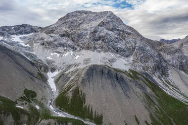 Picturesque scenery of massive rocky mountains with snowy peaks under cloudy sky in Swiss Alps - ADSF45419