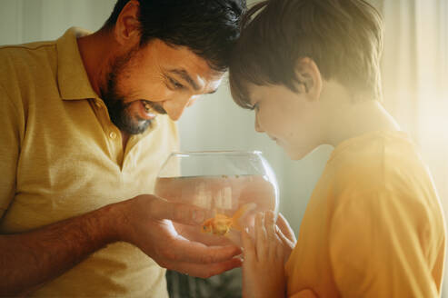 Junge mit glücklichem Vater, der ein Fischglas hält - ANAF01772