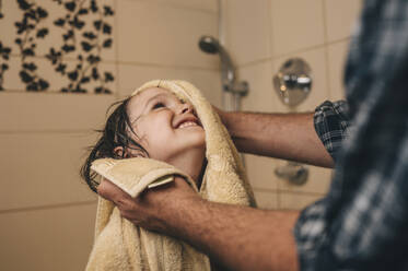 Father wiping happy son with towel in bathroom - ANAF01778