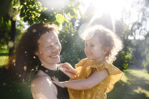 Fröhliche Mutter und Tochter vergnügen sich im Park - EYAF02713