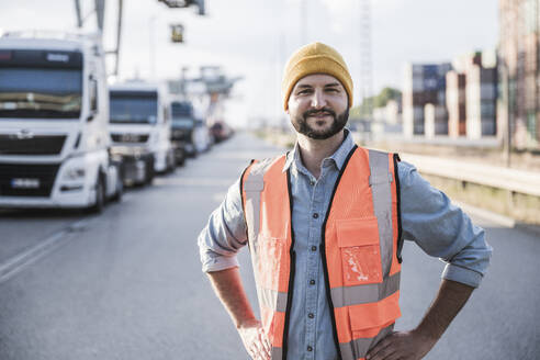 Smiling truck driver standing with hands on hip - UUF29549