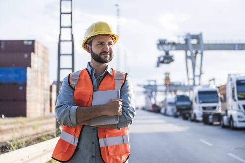 Smiling logistics worker standing in industrial district - UUF29560