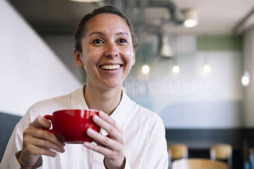 Lächelnde Geschäftsfrau mit Kaffeetasse in einem Cafe - AMWF01548