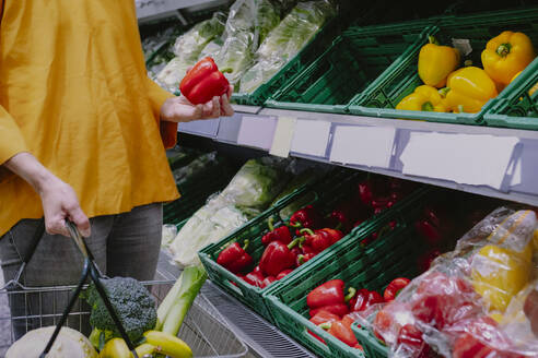 Frau kauft rote Paprika im Supermarkt - AMWF01554