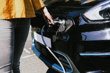 Hands of woman charging electric car - AMWF01559