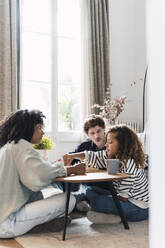 Eltern sitzen im Wohnzimmer und bringen ihrer Tochter das Schachspielen bei - PNAF05641