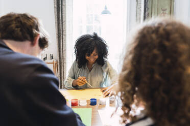 Familie sitzt am Tisch und zeichnet und malt gemeinsam - PNAF05683