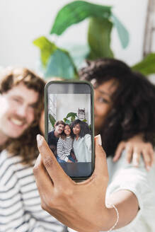 Eine Mutter zeigt stolz ein Familien-Selfie auf ihrem Smartphone - PNAF05696