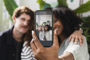 Mutter zeigt stolz Familien-Selfie auf Smartphone - PNAF05697