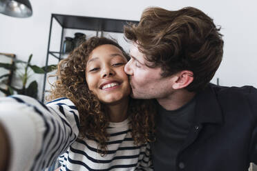 Doting father captures a sweet moment with his daughter as they take a selfie and share a loving kiss - PNAF05718