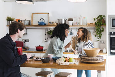 Happy family preparing food together singing and dancing in the kitchen - PNAF05734