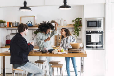 Happy family preparing food together singing and dancing in the kitchen - PNAF05737