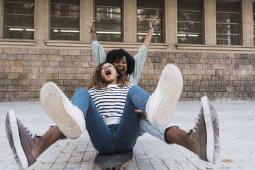 Mother and daughter having fun together sitting on skateboard - PNAF05754