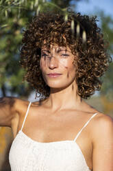 Schöne Frau mit lockigem Haar an einem sonnigen Tag - LMCF00417