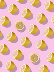 Full frame background with juicy lemon halves set against a bright pink background - ADSF45463