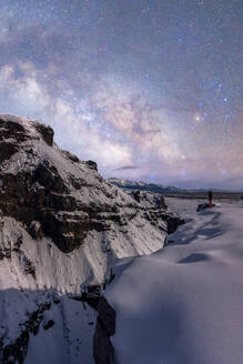 Spectacular scenery of traveler standing on Urbasa Range covered with snow under shiny starry sky in Spain - ADSF45544