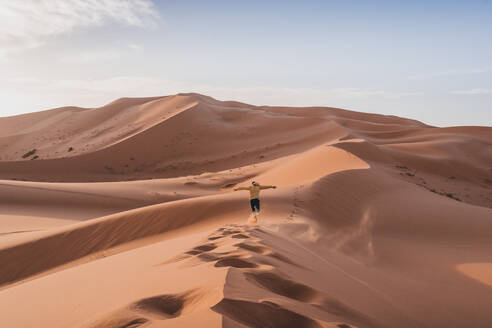 Back view of unrecognizable tourist standing on sand dune and admiring spectacular landscape of Marrakesh desert - ADSF45562
