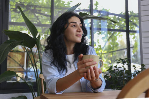 Nachdenkliche Frau mit Kaffeetasse in einem Cafe - SYEF00518