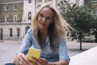 Lächelnde blonde Geschäftsfrau mit Smartphone - AMWF01575