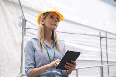 Nachdenklich blickender Ingenieur mit Tablet-PC in der Hand - AMWF01579