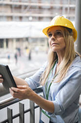 Engineer looking up holding tablet PC near railing - AMWF01605
