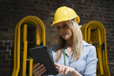 Blond engineer using tablet PC at factory - AMWF01607