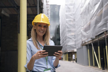 Smiling engineer holding tablet PC at construction site - AMWF01618