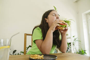 Hungry girl eating burger at home - OSF01878