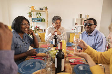 Multikulturelle ältere Freunde beim Abendessen am Esstisch zu Hause - JCCMF10597