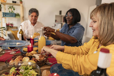 Lächelnde ältere Frau beim Abendessen mit Freunden zu Hause - JCCMF10615