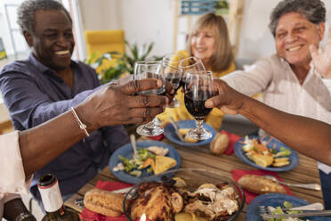 Glückliche ältere Freunde stoßen bei einer Dinnerparty mit Weingläsern an - JCCMF10622