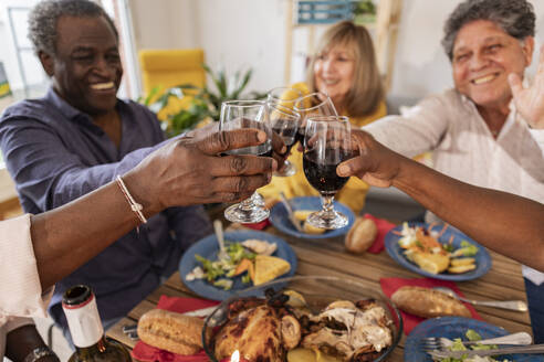 Happy senior friends toasting wineglasses at dinner party - JCCMF10622