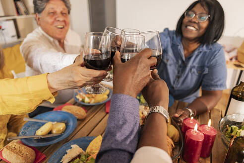 Fröhliche ältere Freunde stoßen bei einer Dinnerparty mit Weingläsern an - JCCMF10623