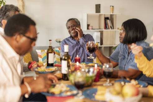 Glücklicher älterer Mann lacht mit Freunden beim Essen auf einer Dinnerparty - JCCMF10634