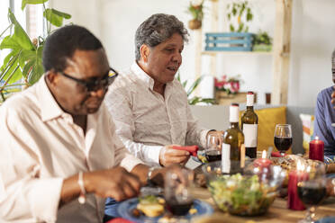 Senior men enjoying dinner sitting at dining table - JCCMF10635