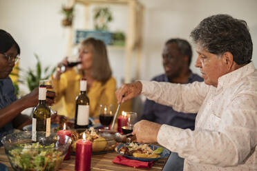 Senior man eating food with friends at dinner party - JCCMF10642