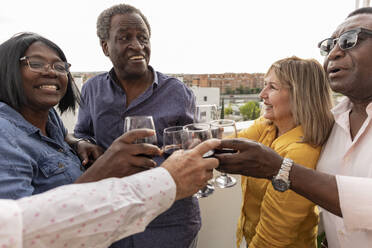 Happy friends toasting drinks in balcony - JCCMF10653