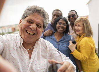 Happy senior man enjoying with friends in background - JCCMF10664