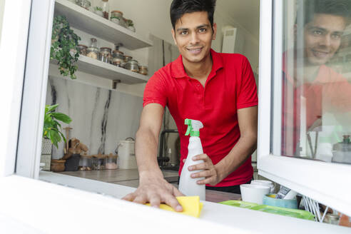 Mann reinigt Küchenfensterbank zu Hause - OSF01883