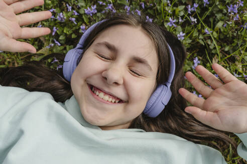 Lächelndes Mädchen, das im Garten liegt und Musik hört - OSF01886