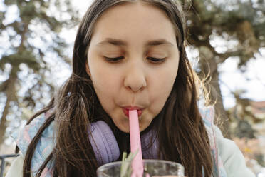 Girl sipping bubble tea from straw at garden - OSF01890
