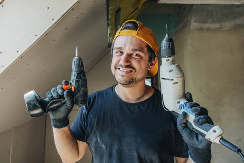 Lächelnder Mann mit Bohrern auf dem Dachboden - VSNF01212