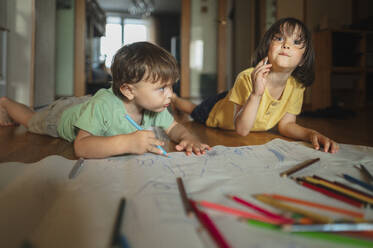 Brüder zeichnen mit Buntstiften auf dem Boden liegend zu Hause - ANAF01799